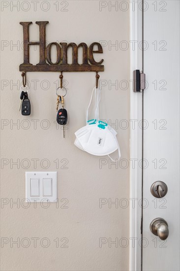 Home key hanger rack next to door with keys and medical face mask during coronavirus pandemic