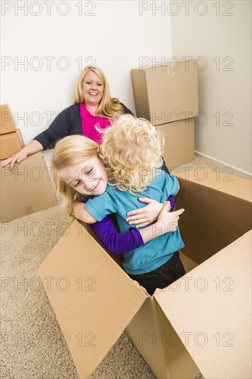 Playful young family in empty room playing with moving boxes