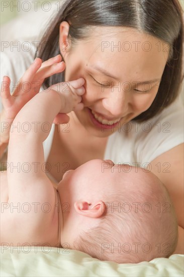 mixed-race chinese and caucasian baby boy laying in bed with his mother