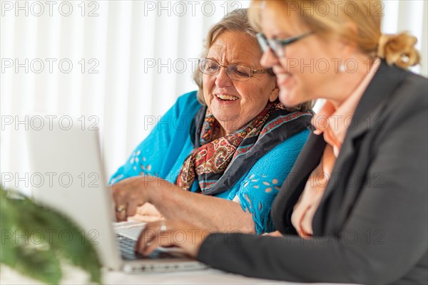 Woman helping senior adult lady on laptop computer