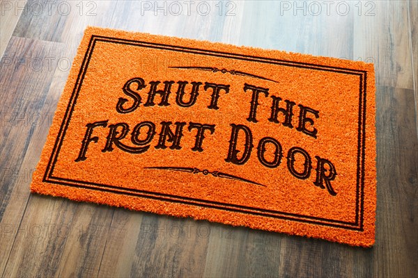 Shut the front door halloween orange welcome mat on wood floor background