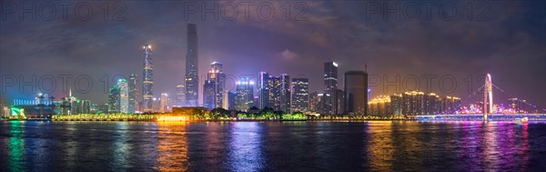 Guangzhou cityscape skyline over the Pearl River with Liede Bridge illuminated in the evening. Guangzhou