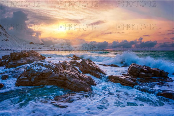 Waves of Norwegian sea on rocky coast in fjord on sunset with sun