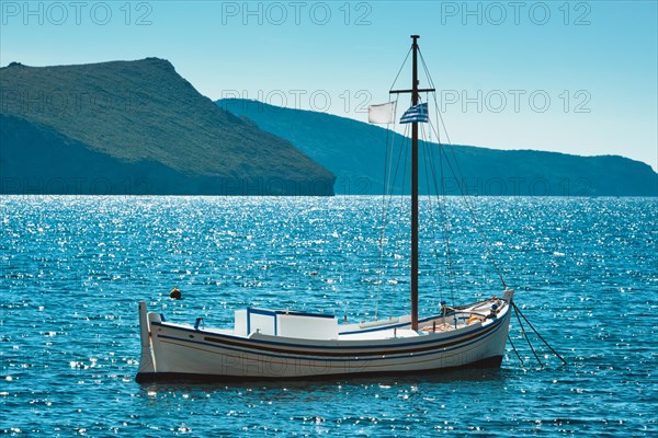 Traditional greek fishing boat in the Aegean sea with greek flag