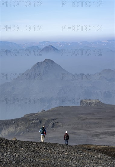 Two hikers on trail through volcanic landscape