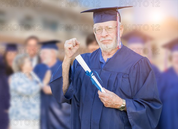 Proud senior man in hat and gown at outdoor graduation ceremony