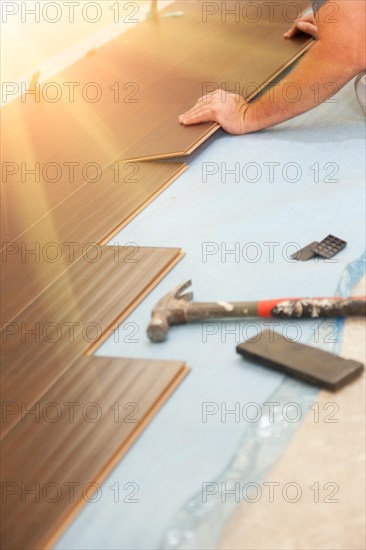 Man installing new laminate wood flooring abstract