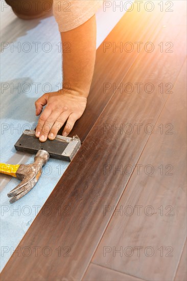 Man installing new laminate wood flooring abstract