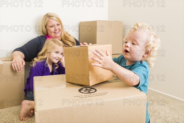 Playful young family in empty room playing with moving boxes