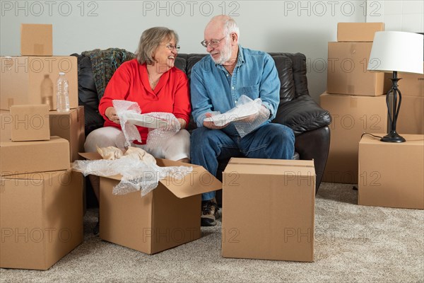 Senior adult couple packing or unpacking moving boxes