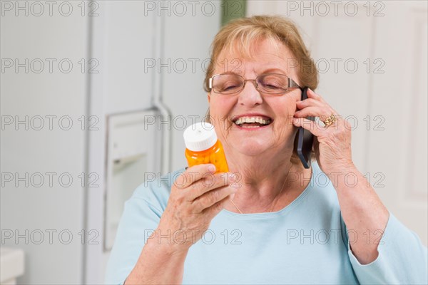 Senior adult woman on cell phone holding prescription bottle