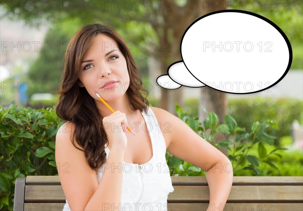 Thoughtful young woman with pencil and blank thought bubble