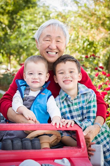 Happy senior adult chinese man playing with his mixed-race grandchildren