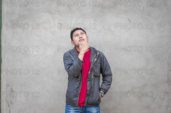 Young man wondering with his hand on his chin on an isolated background