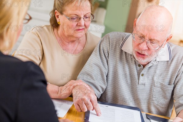 Senior adult couple going over documents in their home with agent at signing