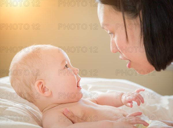 Young mixed-race chinese and caucasian baby boy laying in his bed with his mother