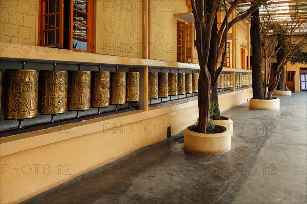 Metal buddhist prayer wheels with buddhist mantra Om mani padme hum in Tsuglagkhang complex in Dalai Lama residence. Mcleodganj