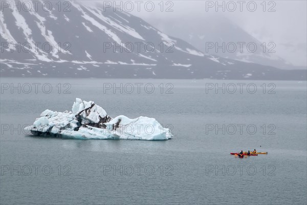 Canoeist in front of iceberg in St. Jonsfjorden