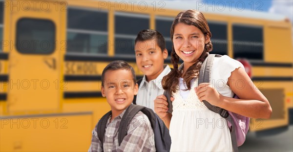 Young hispanic girl and boys walking near school bus