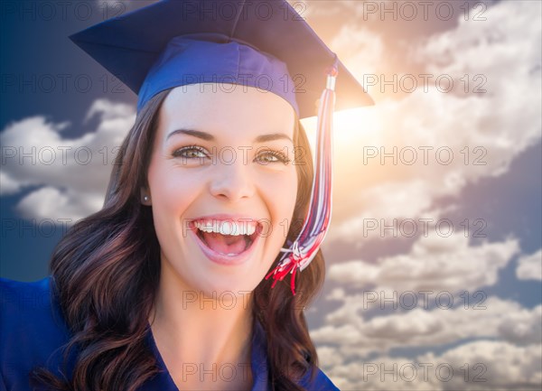Happy graduating mixed-race woman in cap and gown