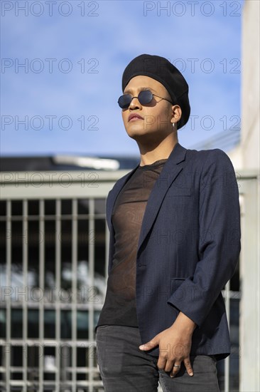 Latin gay male with makeup wearing fashion hat doing catwalk in the street