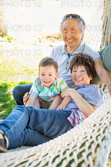 Chinese grandparents in hammock with mixed-race child