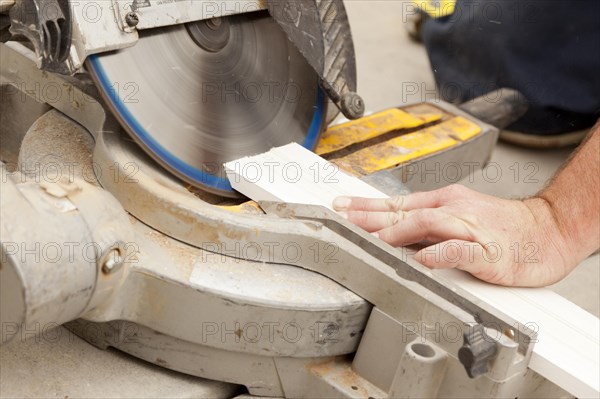 Contractor using circular saw cutting new baseboard for renovation