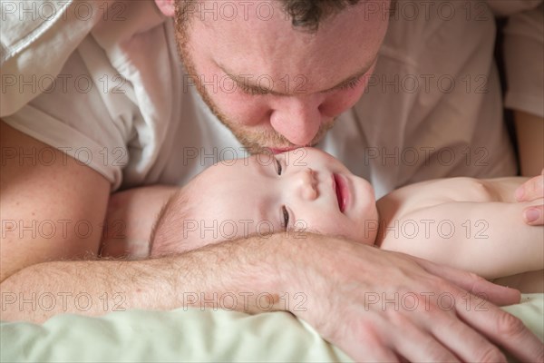 mixed-race chinese and caucasian baby boy laying in bed with his father and mother