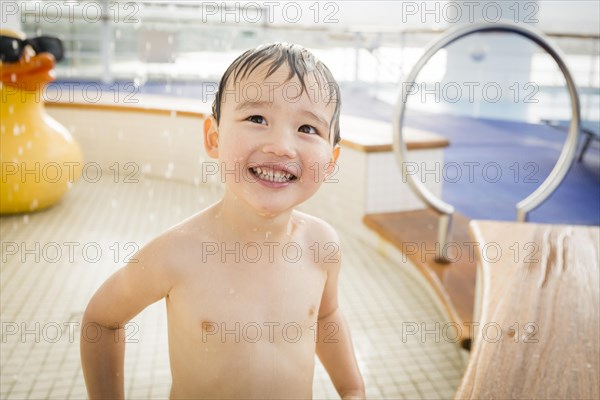 mixed-race boy having fun at the water park with large rubber duck in the background