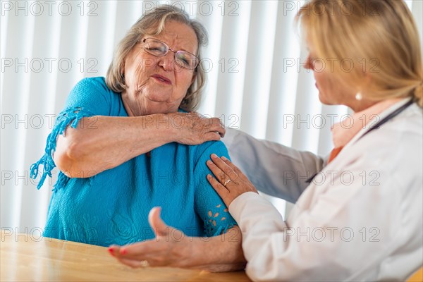 Senior adult woman talking with female doctor about sore shoulder