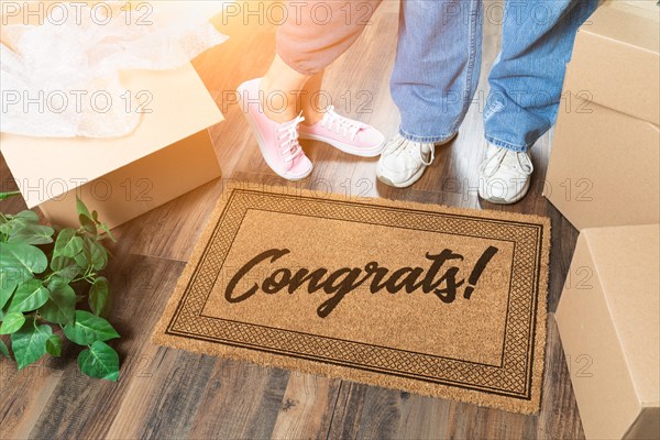 Man and woman unpacking near welcome mat with congrats