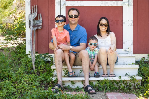 Portrait of caucasian and chinese couple with their mixed-race young boys wearing sunglasses