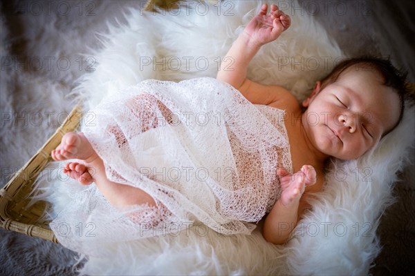 Cute newborn baby boy sleeping in the basket on fluffy blanket