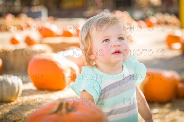 Adorable baby girl having fun in a rustic ranch setting at the pumpkin patch