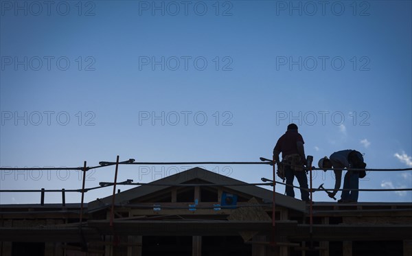 Construction workers silhouette on roof of building