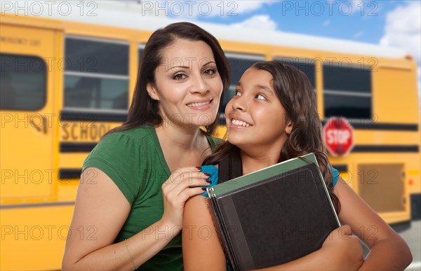 Hispanic mother and daughter near school bus