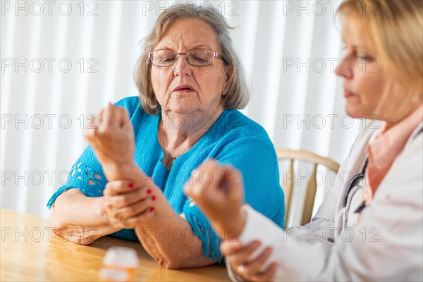 Female doctor talking with senior adult woman about hand therapy
