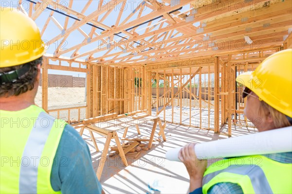 Male and female contractors overlooking new house framing at constrcution site