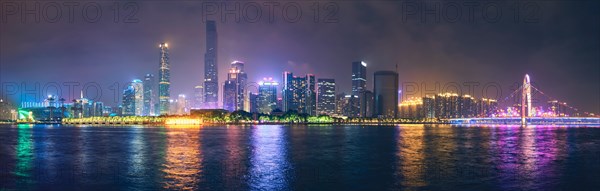 Guangzhou cityscape skyline over the Pearl River with Liede Bridge illuminated in the evening. Guangzhou