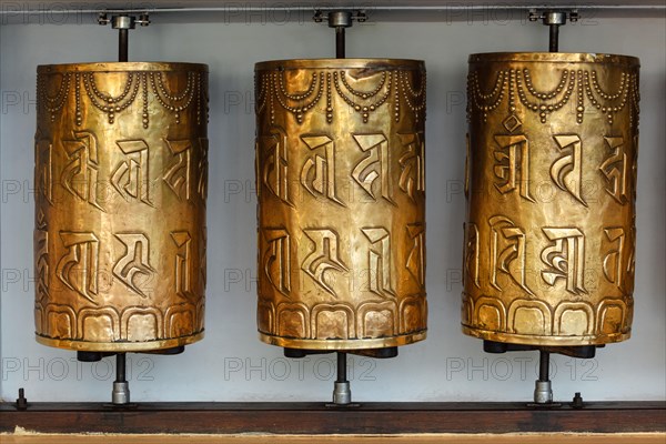 Metal buddhist prayer wheels with buddhist mantra Om mani padme hum meaning Praise to the Jewel in the Lotus in Tsuglagkhang complex in Dalai Lama residence. Mcleodganj