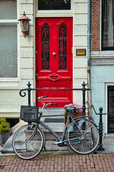 Bicycle near door of old house in Amsterdam street. Bicycles are the very popular means of transport in Netherlands. Amsterdam