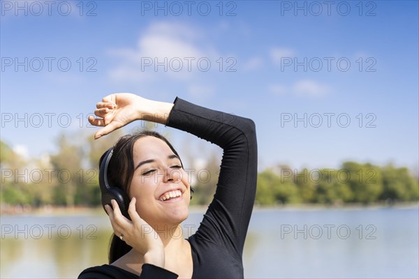 Young woman listening to music outdoors with headphones. Expression of happiness