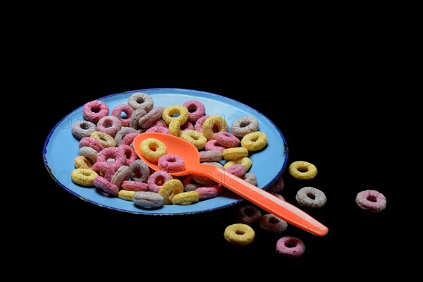 Fruit-flavoured cereal rings in plate with spoon