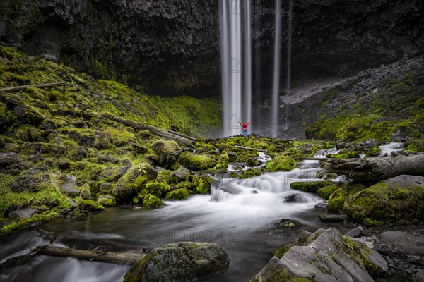 Young woman standing in front of waterfall