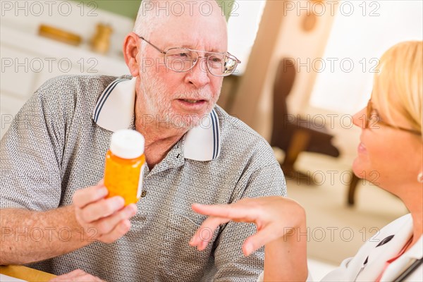 Doctor or nurse explaining prescription medicine to attentive senior man