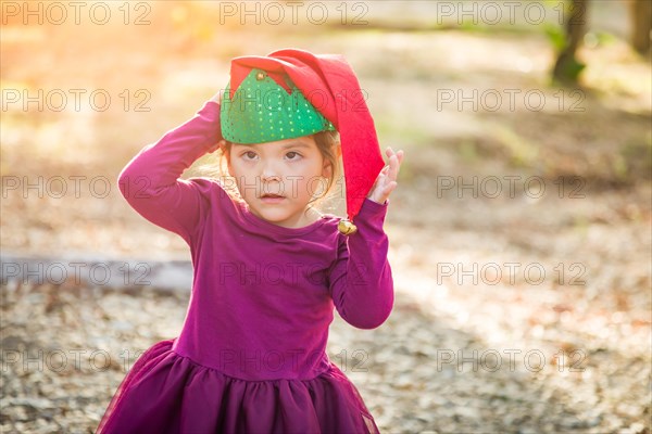 Cute mixed-race young baby girl having fun wearing christmas hat outdoors