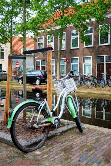 Netherlands popular means of transport bicycle parked near the canal in Delft street with old houses. Delft
