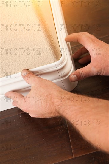 Contractor installing new baseboard with bull nose corners and new laminate flooring renovation abstract