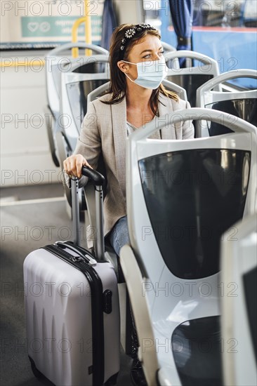 A young woman wearing protective mask commuting by the public bus