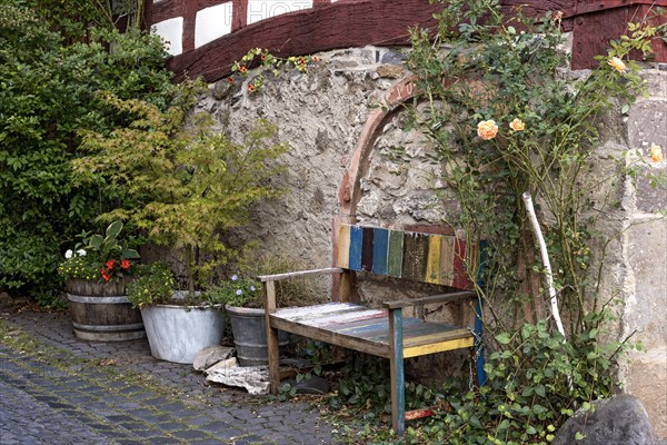 Old colourfully painted faded wooden bench and planter on house wall